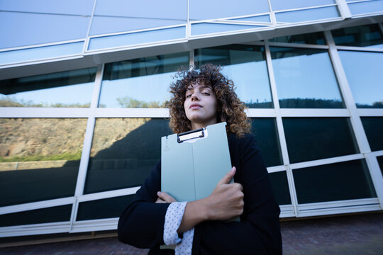 Businesswoman holding clipboard outside modern office building