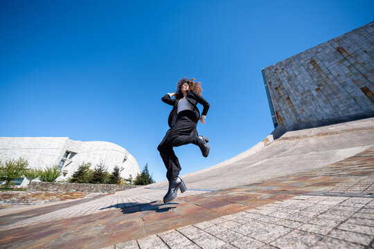 Businesswoman jumping outdoors by modern architecture