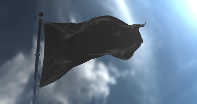 A low angle shot of a solid black flag waving on a metallic flagpole in a seamless loop. The clip captures a smooth slow motion cloth simulation against a cinematic blue sky background filled with bri
