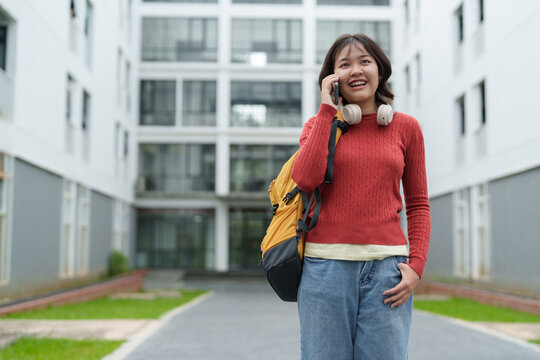 Asian female student talking on phone outside campus building