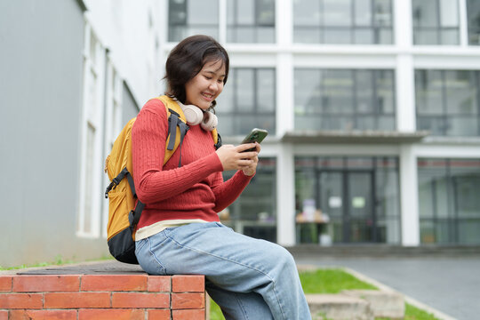 Asian college student smiling checking phone on campus