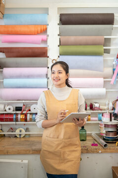 Gift packaging retail woman worker using a tablet in a colorful wrapping paper and ribbon shop