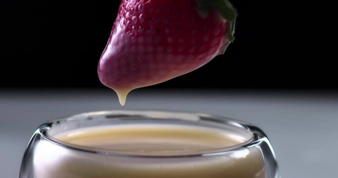 Fresh strawberry dipping into sweet condensed milk cream macro close up video