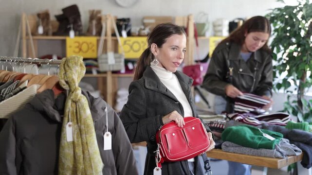 Selective middle-aged woman looking for little shoulder bag during sell-out in retail outlet 