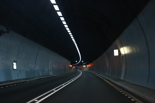 A dark curved road inside a modern tunnel.