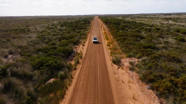 A 4x4 driving on a corrugated road, filmed by a drone from the front of the car