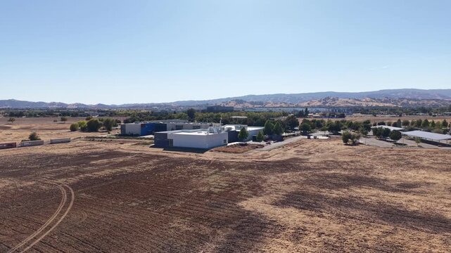 High angle drone footage showing the Solano Community College campus in Vacaville, California, surrounded by dry fields and distant hills under a clear blue sky on a sunny day