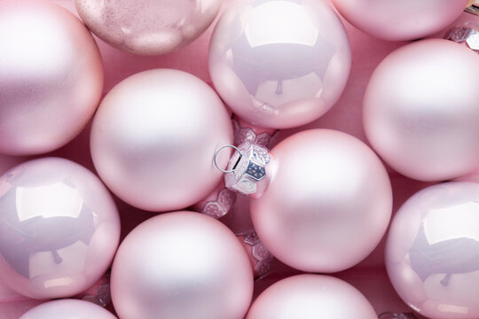Close-up of a pile of light pink Christmas tree baubles of varying  textures. Flat lay