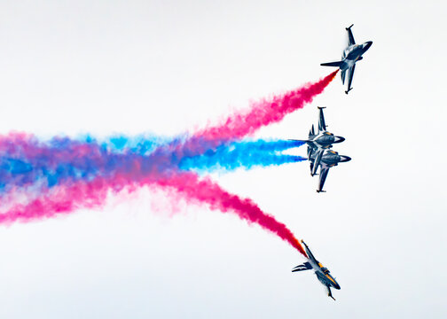 Aerial view of Korea Black Eagles fighter jets performing an aerobatic display with red and blue smoke trails above Changi Exhibition Centre in Singapore, Singapore.