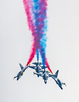Aerial view of the Black Eagles aerobatic team performing a formation flight with red and blue smoke trails above the Changi Exhibition Centre in Singapore, Singapore.