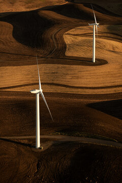 Aerial view of wind turbines standing in rolling hills of a wind farm at sunset in Rio Vista, California, United States.