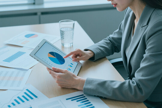 Caucasian businesswoman reviewing sales analytics on tablet, comparing charts and reports during office meeting. Ideal for business strategy, financial planning, data analysis marketing