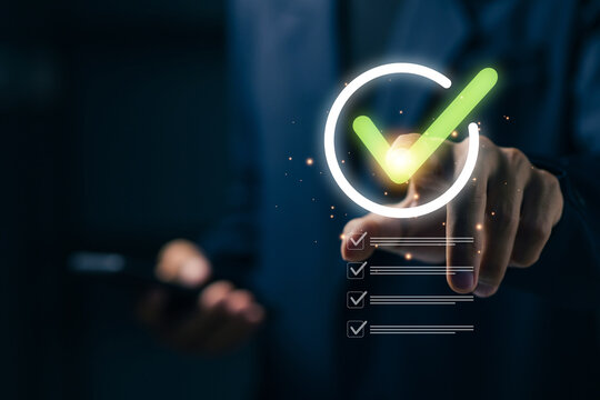 Business professional touching a virtual green check mark and checklist, representing quality assurance, approval, verification, compliance, task completion, and business workflow.