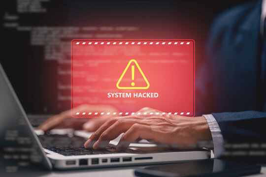 Business professional typing on a laptop with a red system hacked warning, representing cyberattack, cybersecurity breach, malware threat, data security risk, hacking, and online protection.