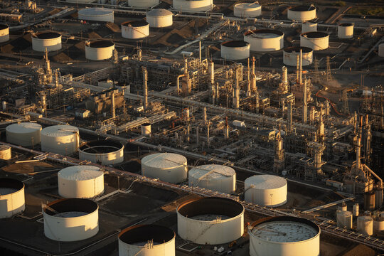 Aerial view of Chevron Richmond Refinery with storage tanks, industrial processing units, and pipelines under warm golden hour light in Richmond, California, United States.