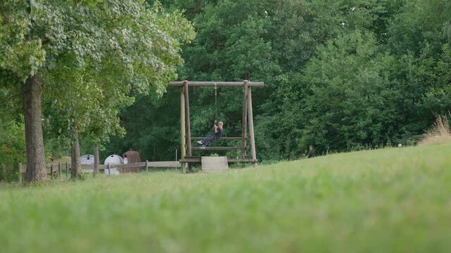 A boy jump on a zip line rope swing low angle slow motion outdoors