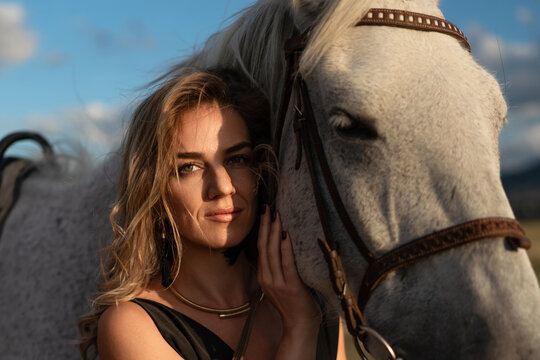 Woman horse portrait attractive blonde embraces dappled grey horse outdoors during golden hour