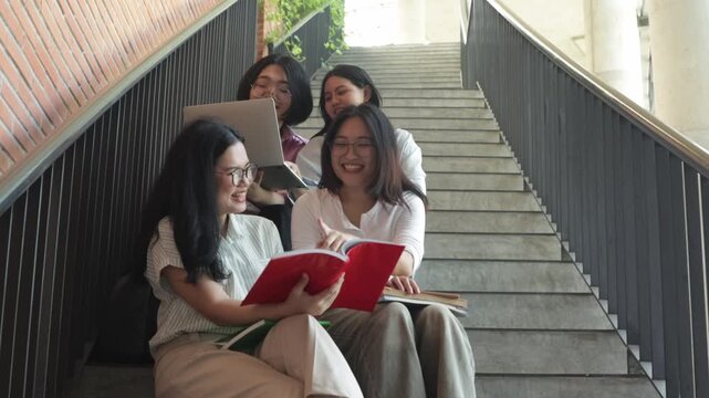 Group cheerful asian male and female students carrying backpacks and textbooks sit steps academic building smile and wave camera in front university building ready begin university studies.