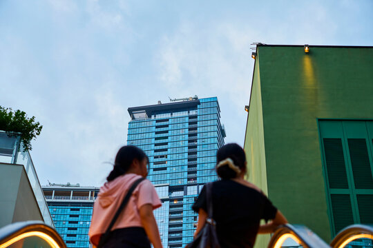 People riding escalator towards modern buildings in shenzhen
