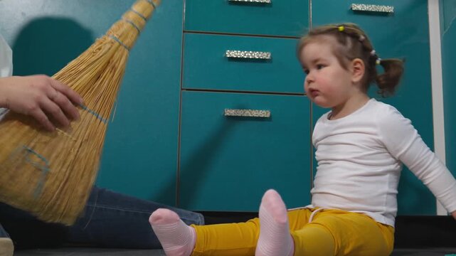 Preschool girl practices sweeping beside her young kindergarten teacher during a practical activity. The Montessori approach develops motor abilities, self reliance, attention, and everyday skills. Mi