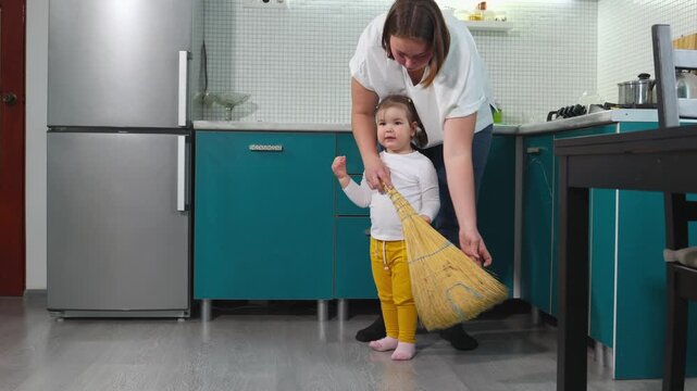 Young Caucasian teacher demonstrates sweeping to a little girl during a kindergarten lesson. The Montessori educational activity develops coordination, attention, responsibility, and practical abiliti