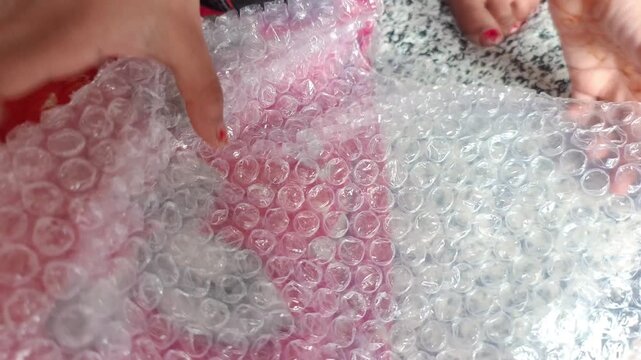 Close up of hands popping plastic bubble wrap packaging material