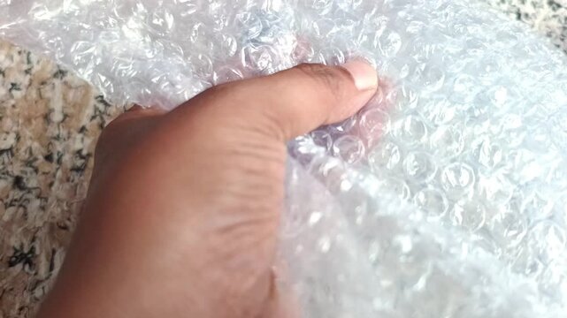 Close up of hands popping plastic bubble wrap packaging material