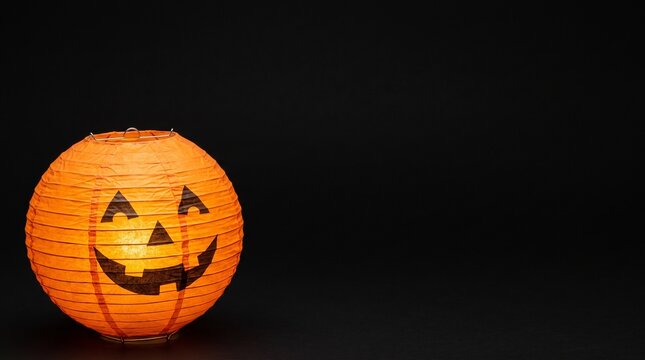 Orange paper lantern decorated with a jack o lantern face for Halloween celebration