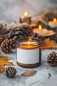 Amber glass jar candle with blank label and pinecones on tabletop for autumn scented candle mockup and cozy background