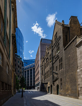 London - 07 24 2022: View of Shoe Ln. Narrow urban street flanked by tall buildings in contrasting styles: older stone fa&ccedil;ades with rectangular windows on one side and dark brick structure with arched