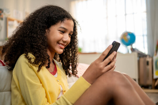 African American teenage girl using cellphone while sitting on the floor. 