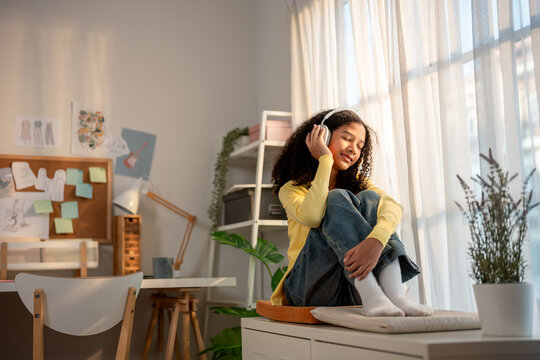 African American teenage girl wearing headphones and nodding head to the beat.