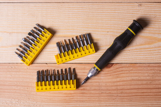 Precision screwdriver bit set with interchangeable tips on rustic wooden workbench surface