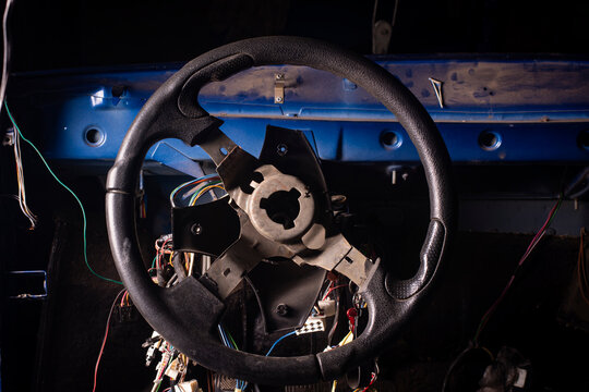 Disassembled steering wheel without horn horn-button cap inside gutted car dashboard cabin body