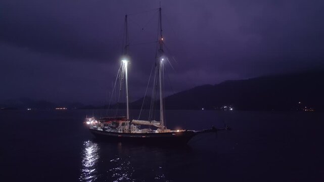 Big expeditional sailing boat anchored in the calm sea at night. Drone night shot