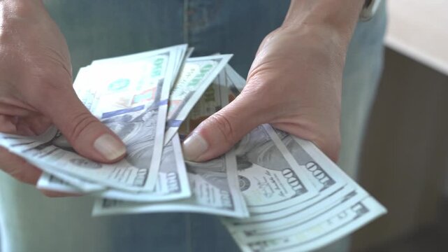 A woman counts money while standing. Close-up. The woman shows how much money she has.