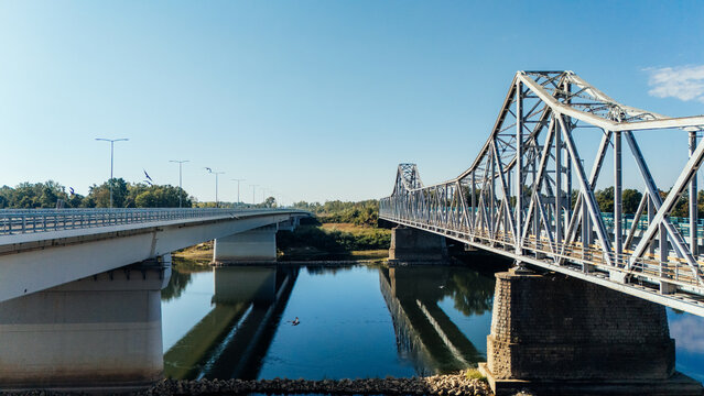 Aerial view of Racha Bridge featuring its historic steel truss structure alongside a modern concrete bridge over the Sava river under a clear blue sky in Sremska Raca, Vojvodina, Serbia.