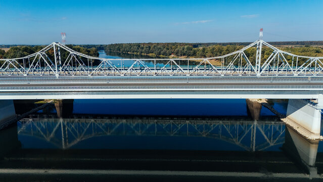 Aerial view of Racha Bridge spanning the Sava River, with steel truss structure, calm water reflecting the bridge, and lush riverbanks in Sremska Raca, Vojvodina, Serbia.