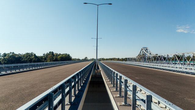 Aerial view of the Racha Bridge spanning the Sava River with modern asphalt lanes and steel railings under a clear blue sky in Sremska Raca, Vojvodina, Serbia.