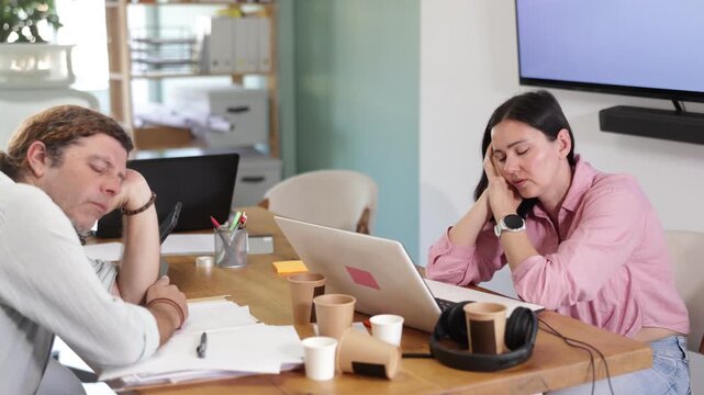 Exhausted middle-aged man and woman sleeping at workplace after long stressful workday in office . High quality 4k footage