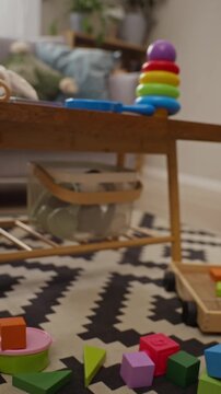 Vertical video of colorful educational toys and blocks scattered on living room floor zooming out. Clip fits parenting commercials, daycare advertisements, and early childhood learning campaigns