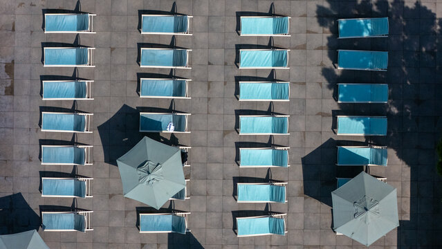Aerial view of rows of blue lounge chairs and umbrellas arranged on a paved pool deck at Los Angeles International Airport. Los Angeles, California, United States.