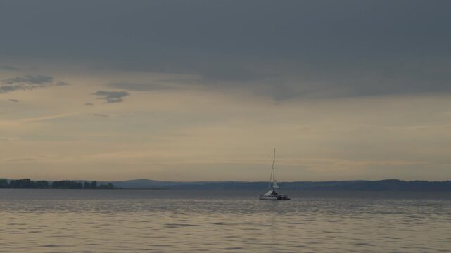 Sailing boat moves on the lake with during sunset