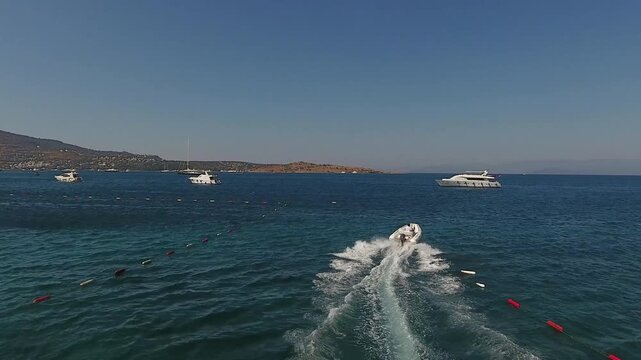 Aerial view of a fast motorboat leaving a white wake on the turquoise sea of Bodrum Bay
