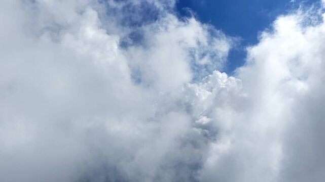 Rolling white clouds against a bright blue sky background