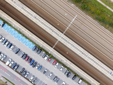 Aerial view of railway station tracks, passenger platforms and adjacent parking area