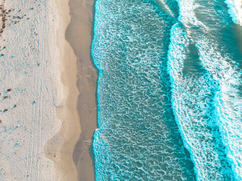 Aerial view of turquoise ocean waves crashing onto the white sandy shoreline at Wrightsville Beach, North Carolina, United States.