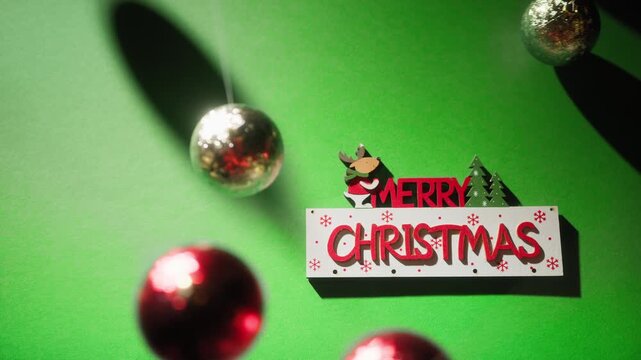 Merry Christmas Text Over Swinging Balls