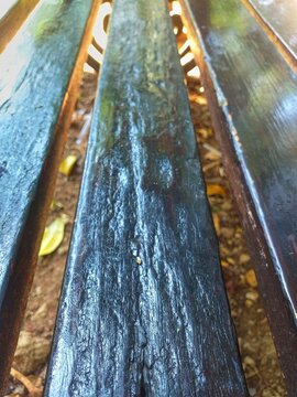 Vertical picture of weathered dark wooden park bench slats suitable for rustic outdoor scenes, garden furniture catalogs, outdoor themed designs, and vintage aesthetics.