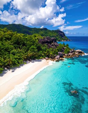 An aerial drone view captures a pristine tropical beach with turquoise waters and lush green hills.